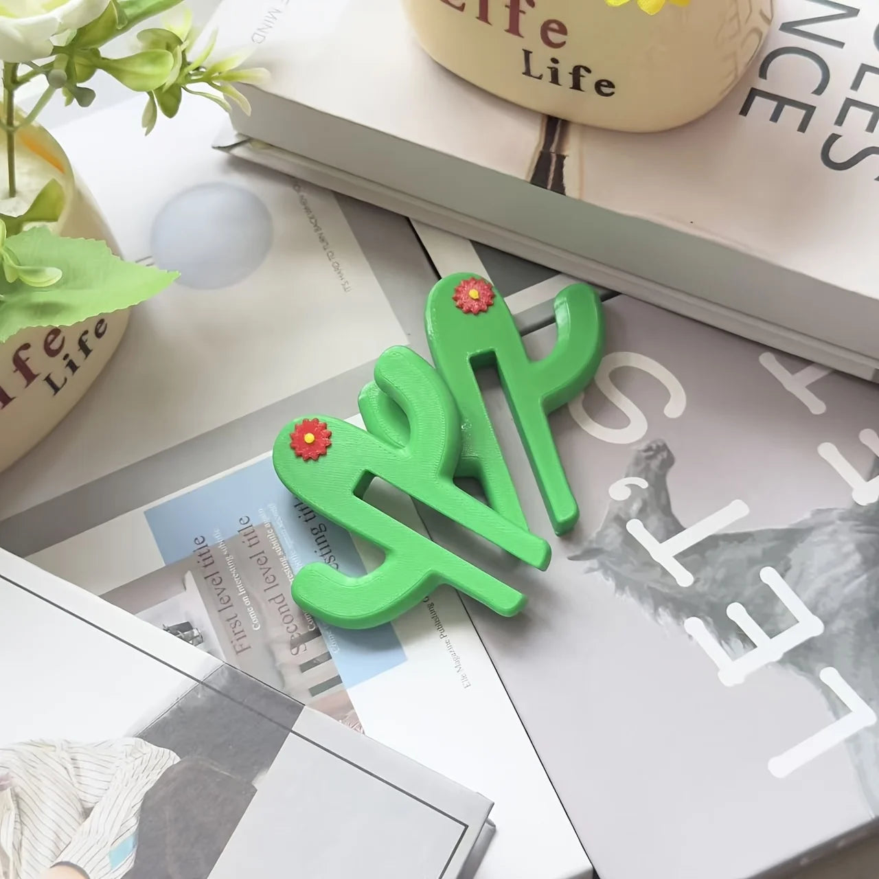 Green cactus shaped bathroom hook hanging over a glass shower door holding towels and accessories close up view