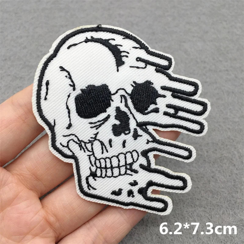Skull and hand patch held by a hand on a gray background