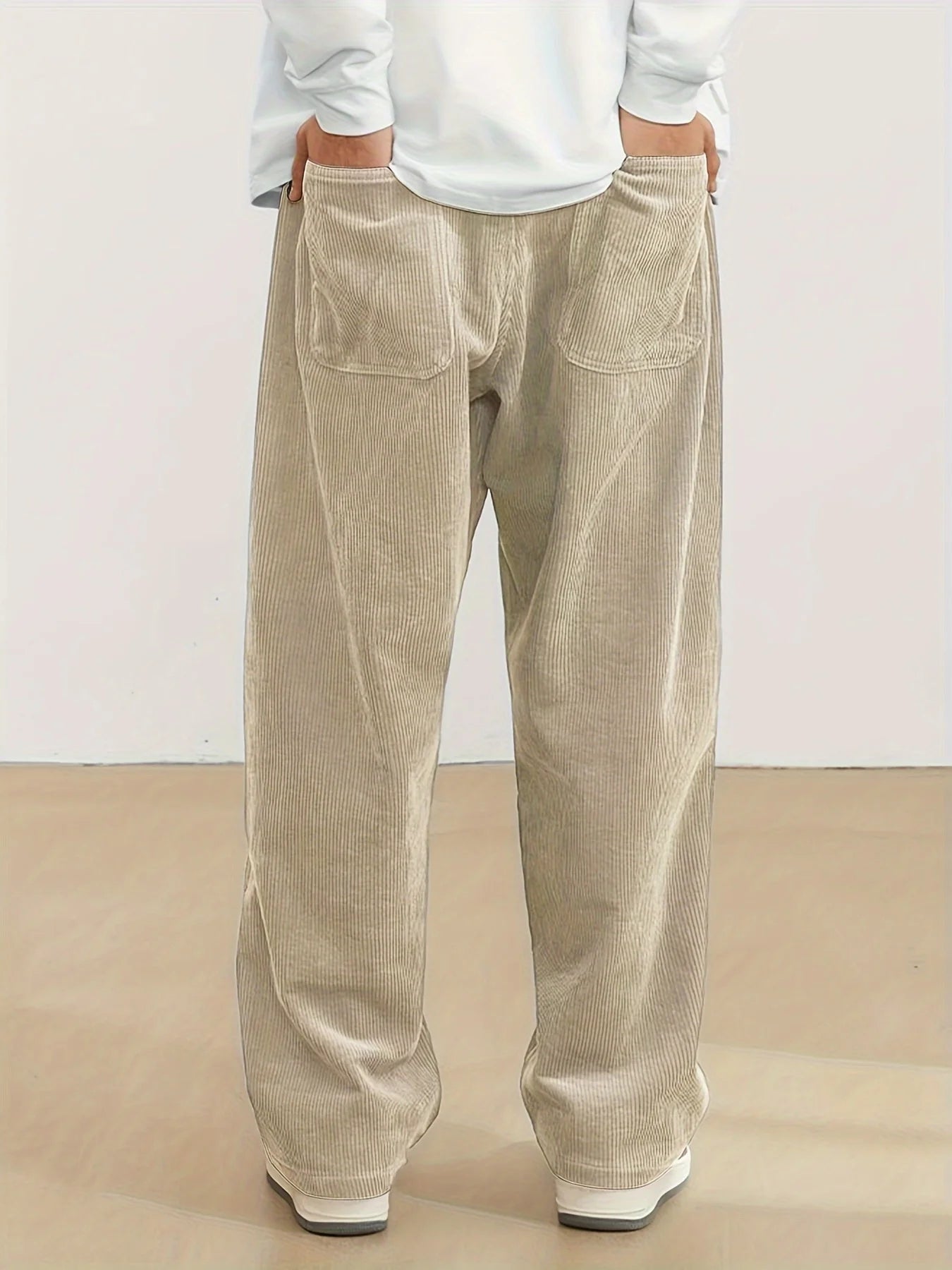 Beige corduroy pants worn by a person on a plain background