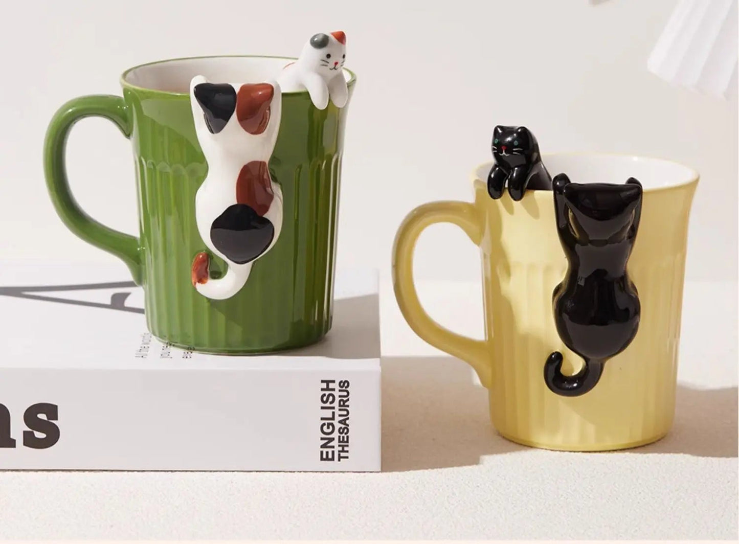 Green and yellow ceramic cat mugs with a 3D cat climbing over the rim.