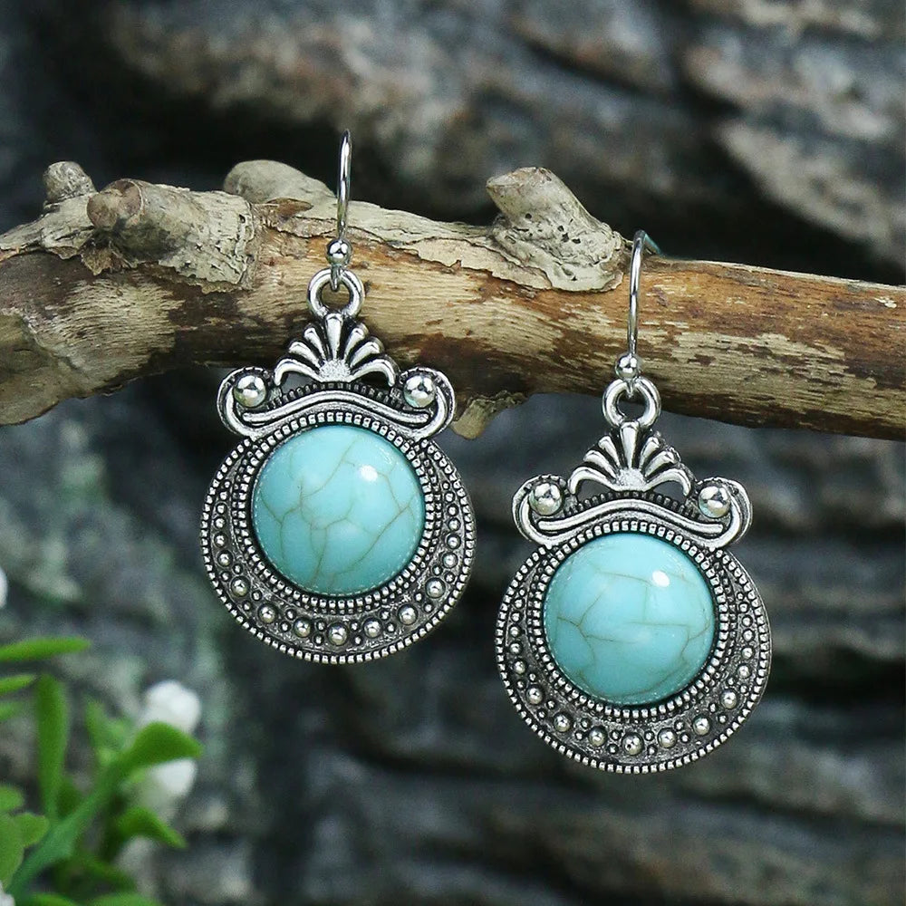 Turquoise earrings with silver detailing on a wooden branch