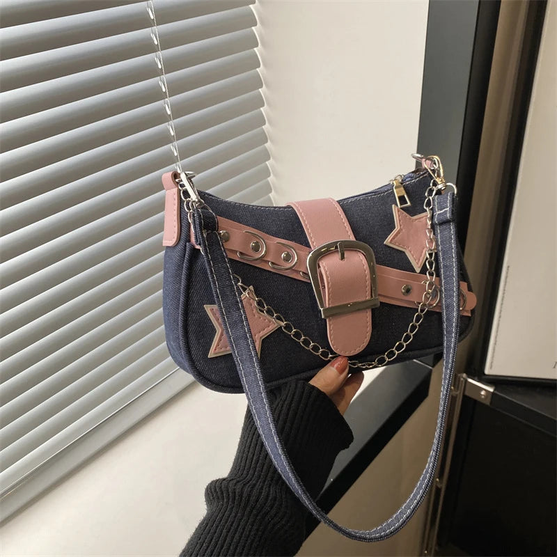 Handbag with star designs and a chain detail held by a person in front of a window.