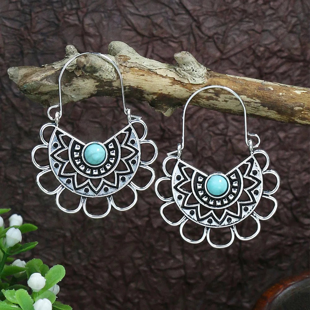 Silver earrings with turquoise stones on a wooden branch