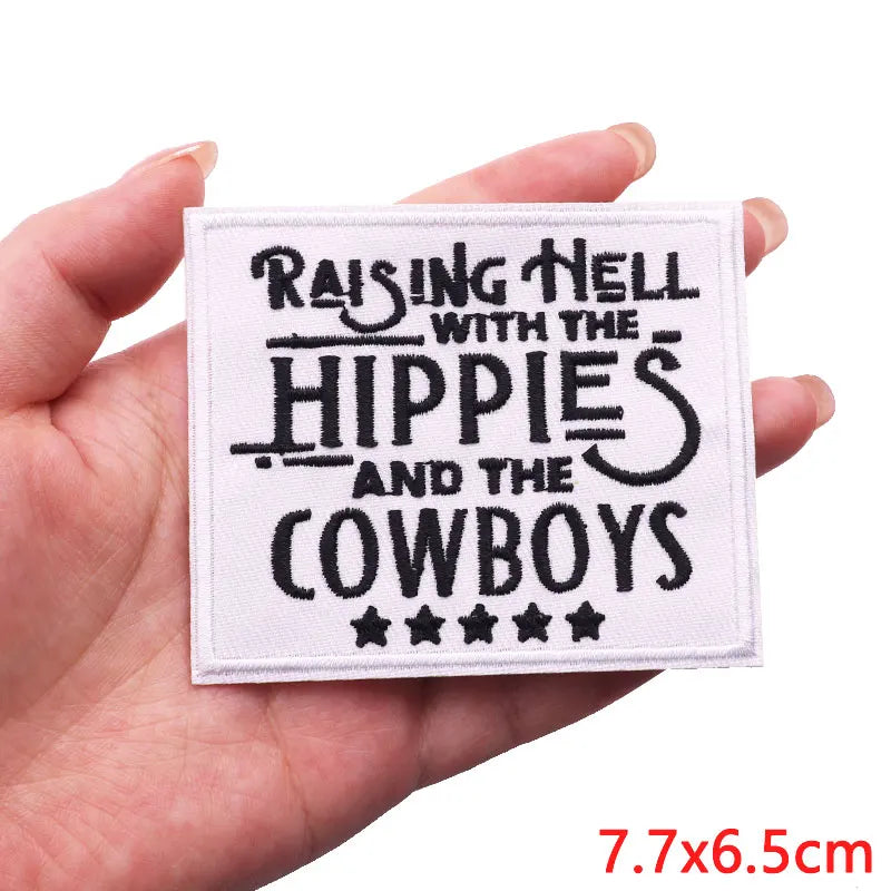 Patch with text 'Raising Hell with the Hippies and the Cowboys' held in a hand.