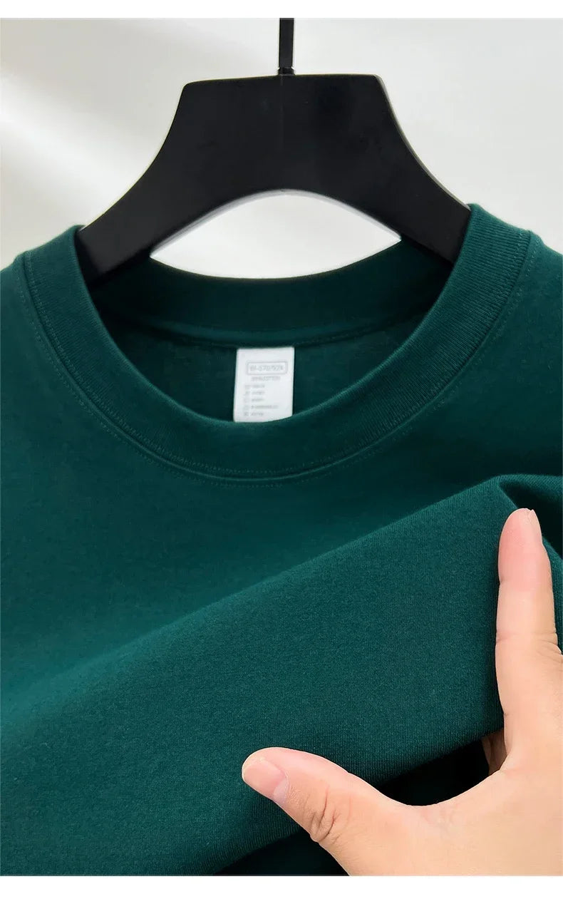 Green sweatshirt on a hanger with a hand touching the fabric