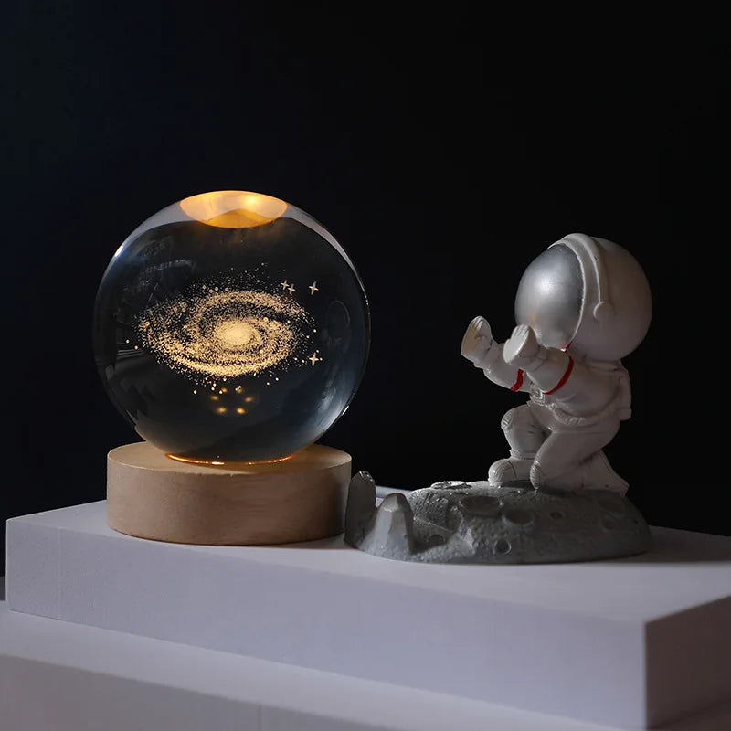 Glass ball with galaxy design next to an astronaut figurine on a dark background