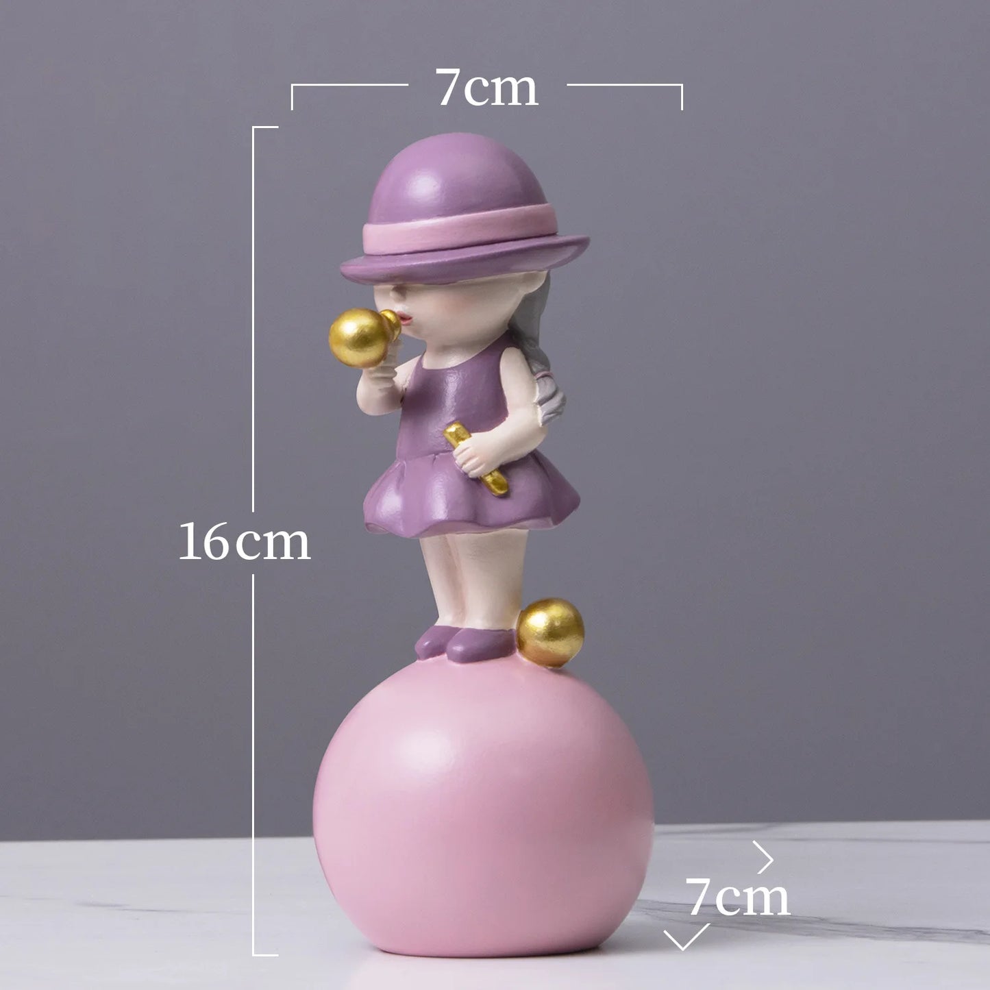 Decorative figurine of a girl in a purple outfit and hat on a pink ball, with measurements indicated.