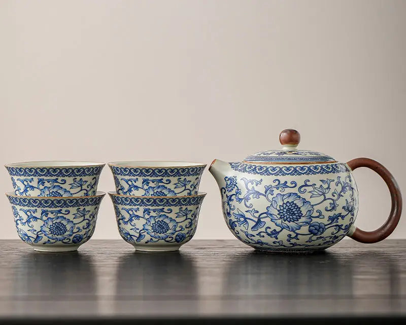 Ceramic teapot and cups with blue floral patterns on a wooden surface.
