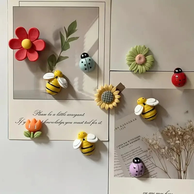 Decorative magnets shaped like flowers and bees on a white surface with text and plants.