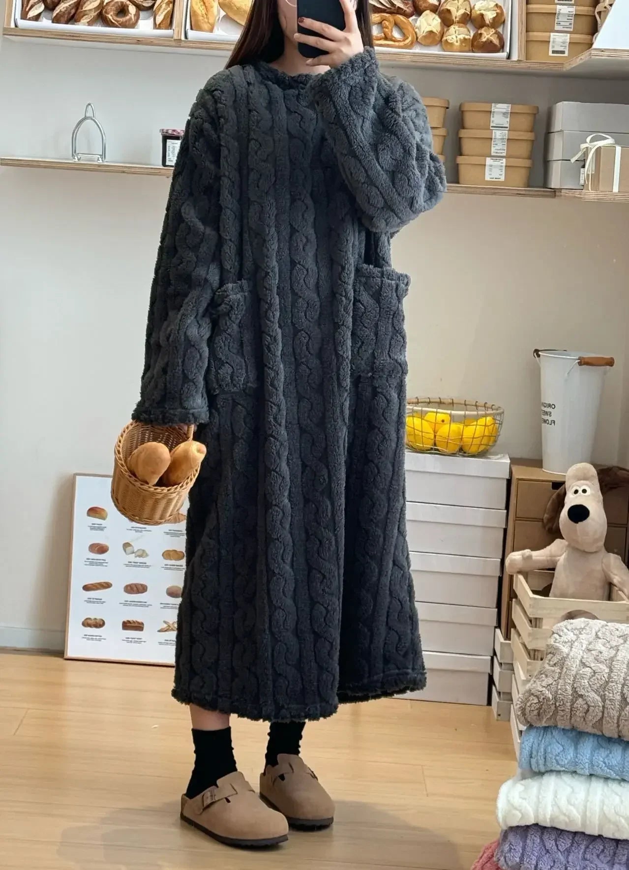 Person wearing a long dark blue cable knit sweater in a store setting.