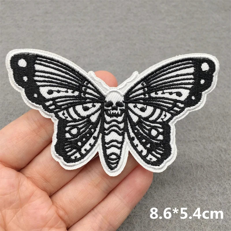 Butterfly-shaped patch held by a hand on a gray background