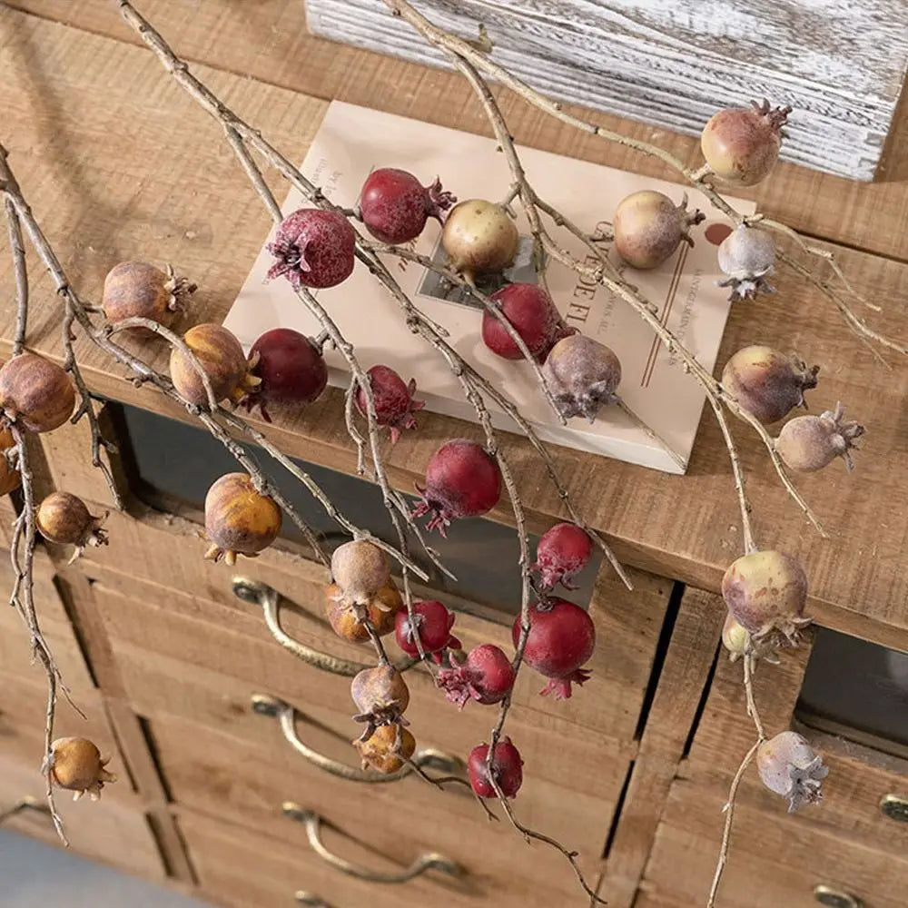 Decorative branches with pomegranate-like fruits on a wooden surface