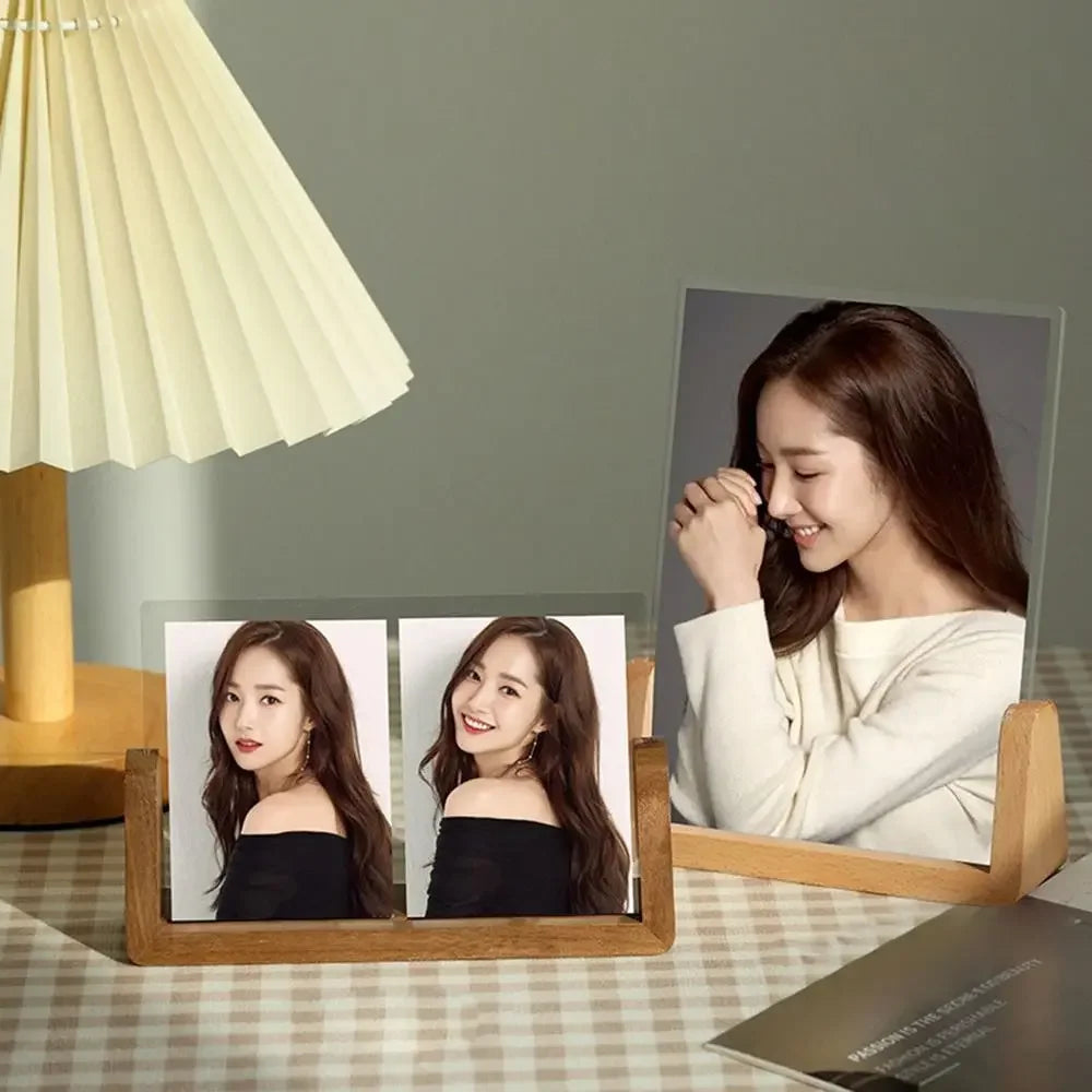 Wooden photo frame with two portrait photos of a woman on a table with a lamp in the background.