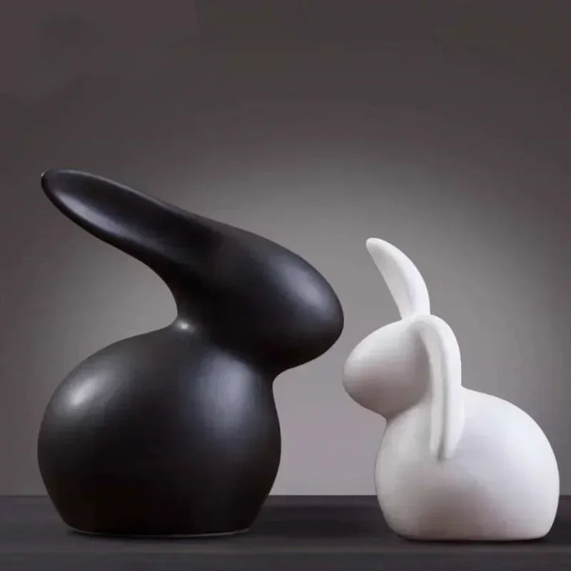 Black and white rabbit-shaped sculptures on a dark surface with a gray background