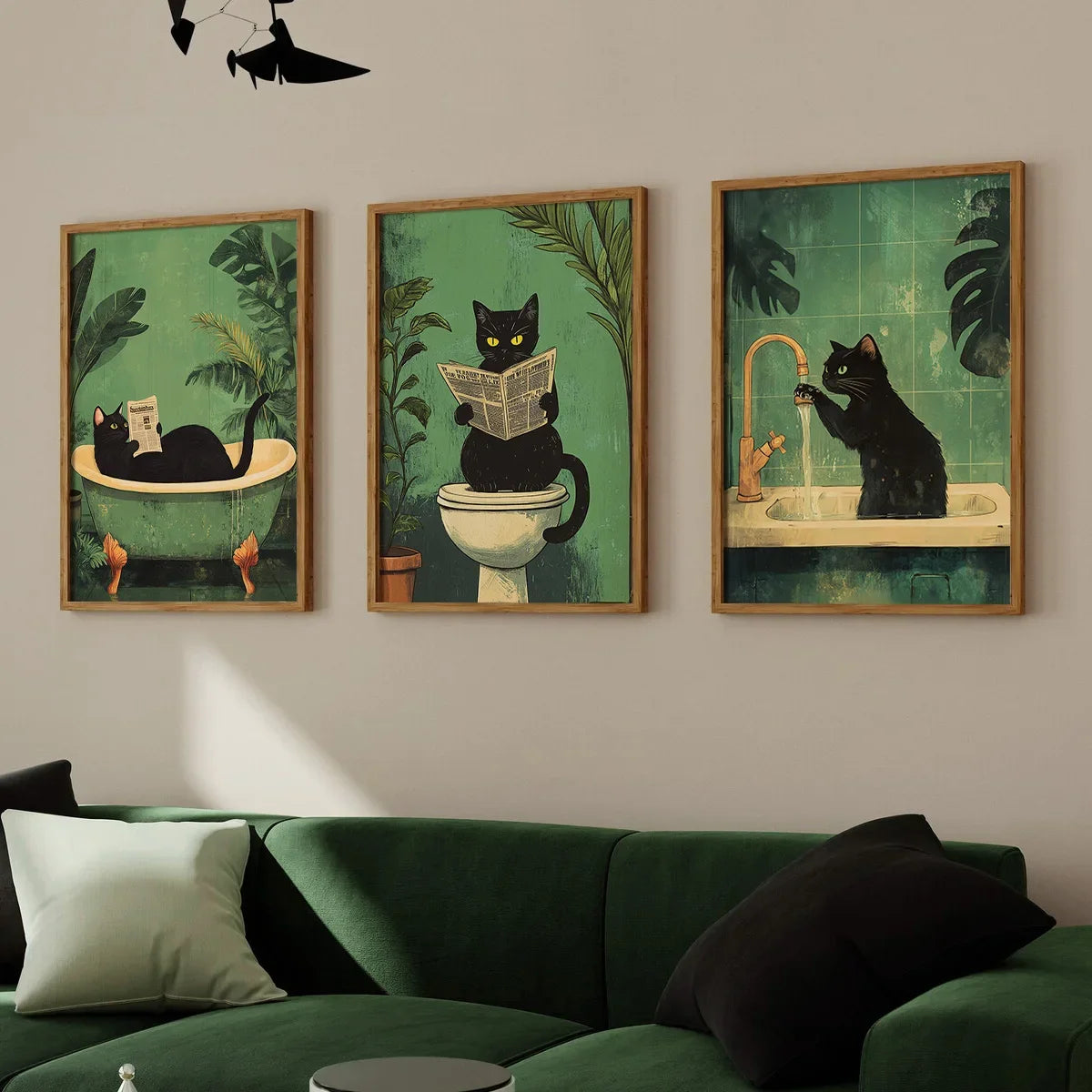 Three framed artworks of cats in a bathroom setting on a wall above a green sofa.