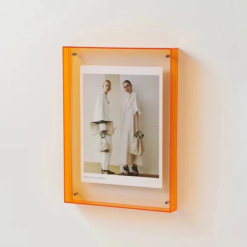 Orange frame with a photo of two people wearing white outfits on a white wall.