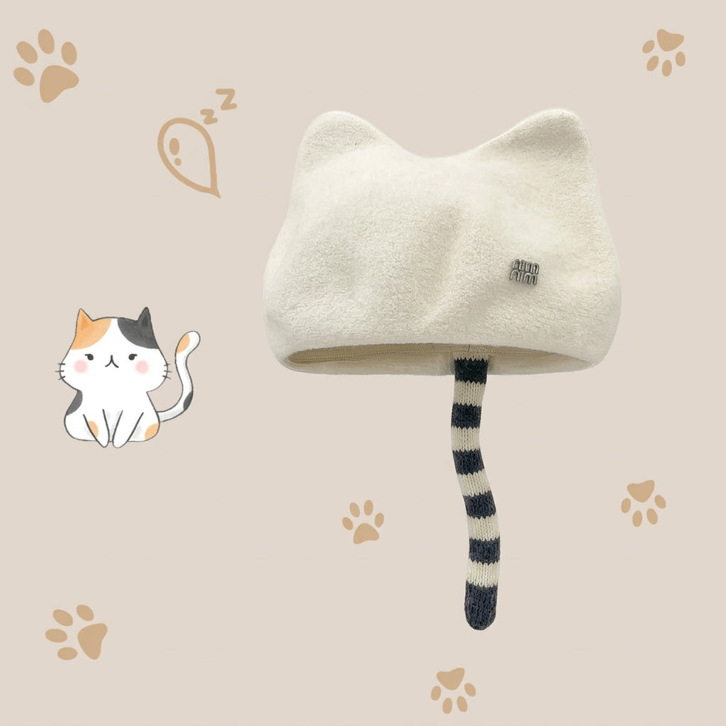 A cream-colored cat-ear hat with a long tail detail and a small square logo patch, shown on a beige background with paw prints and a cartoon cat illustration. 