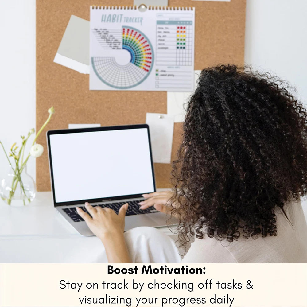 Person using a laptop with a calendar and habit tracker on a corkboard in the background.