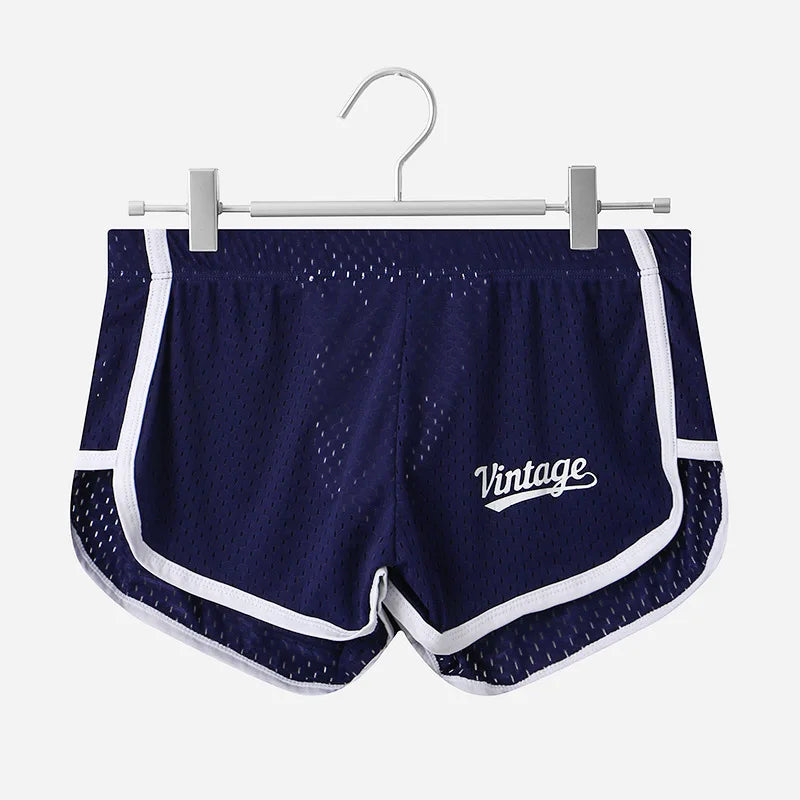 Navy blue athletic shorts with white accents on a hanger against a white background