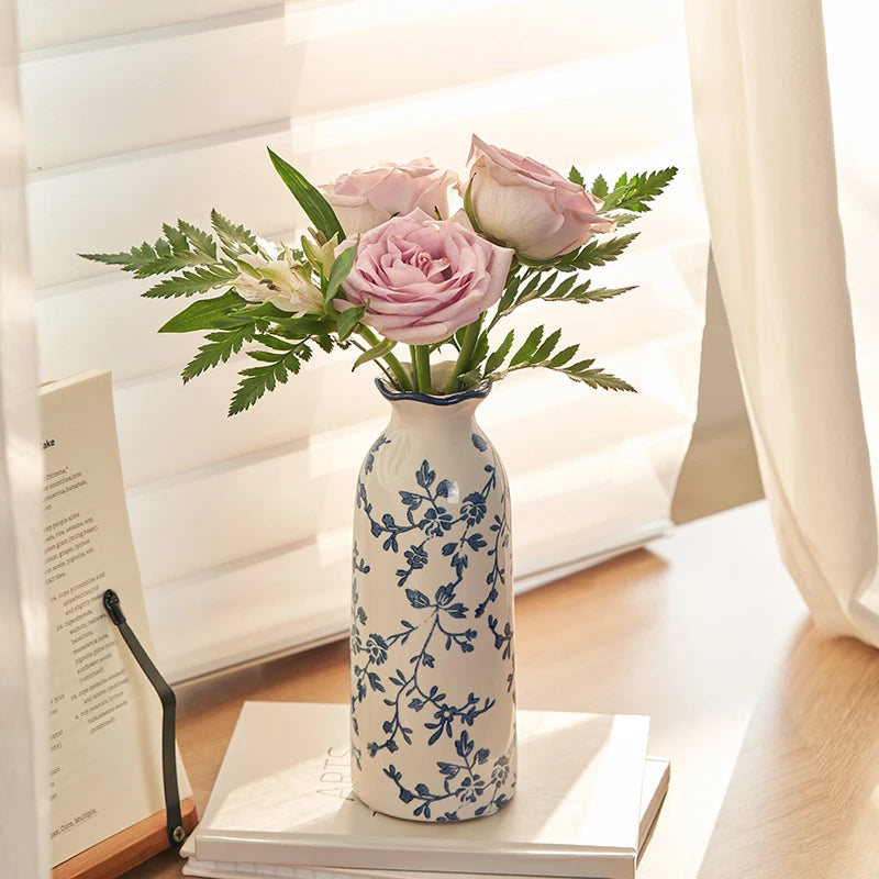 Floral arrangement in a decorative blue vintage vase on a table with books