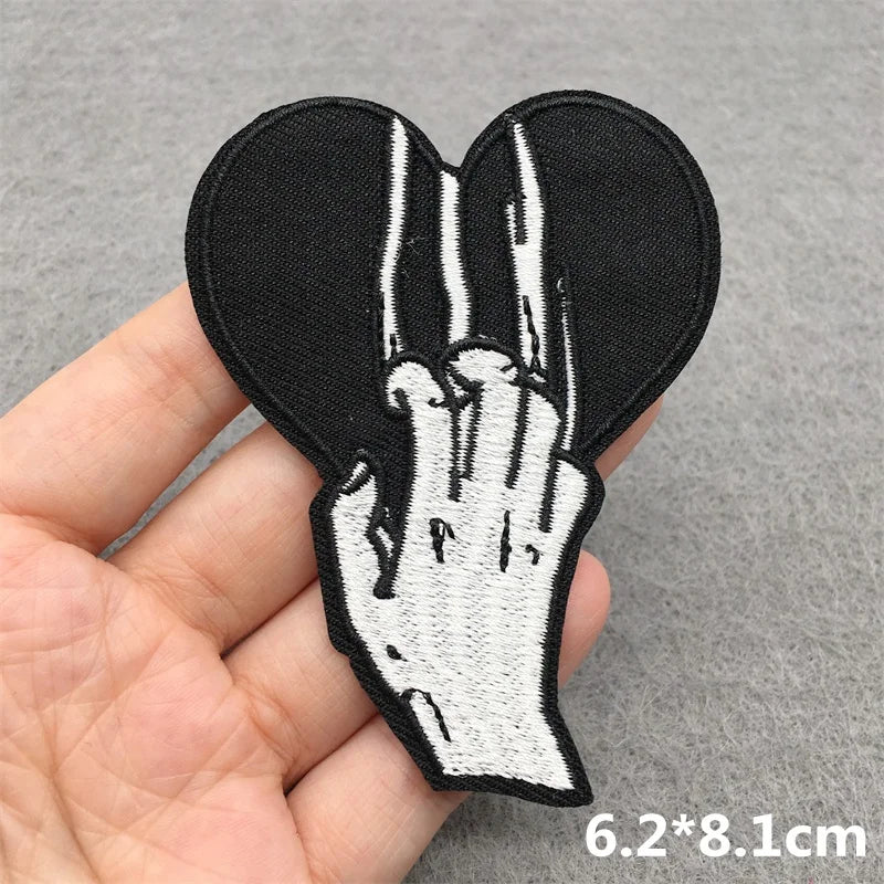 Embroidered patch of a hand making a peace sign held in a hand on a gray background