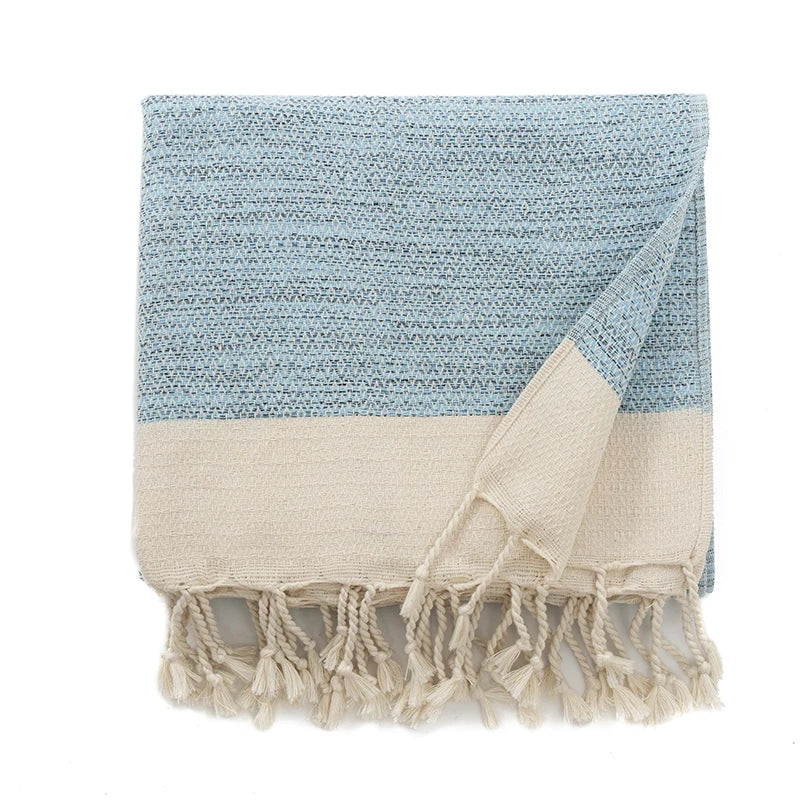 Two-tone blue and beige throw with tassels on a white background