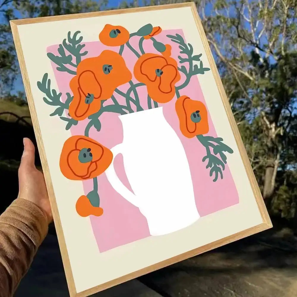 Framed artwork with orange flowers and a pink background held outdoors.