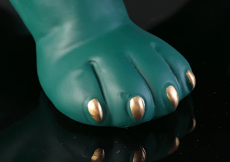 Teal paw with gold claws on a reflective black surface