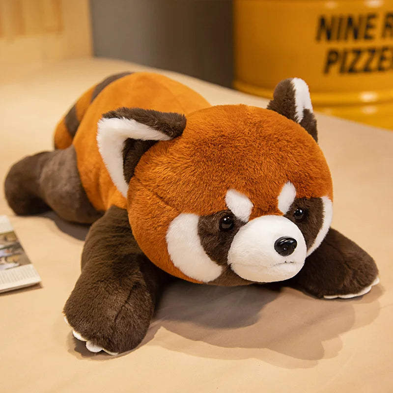 Plush toy red panda lying on a surface with a blurred background