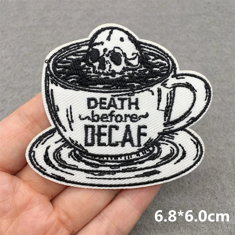 Embroidered patch of a coffee cup with a skull and 'Death before Decaf' text on a gray background.