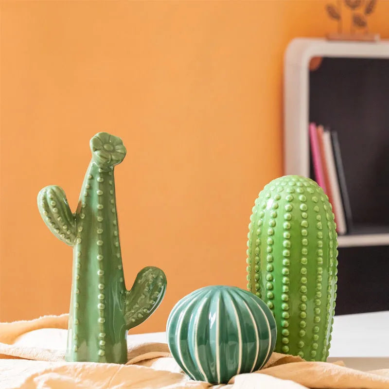 Three green cactus-shaped objects on a surface with an orange wall in the background.