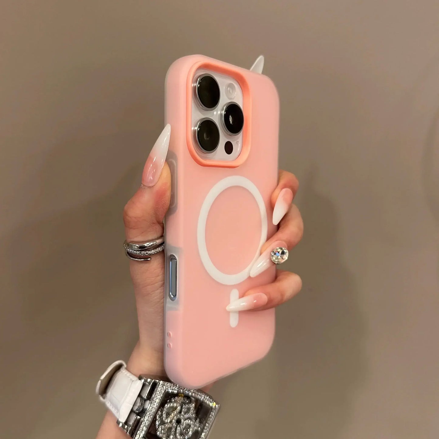 Hand holding a pink phone case with a symbol design against a neutral background