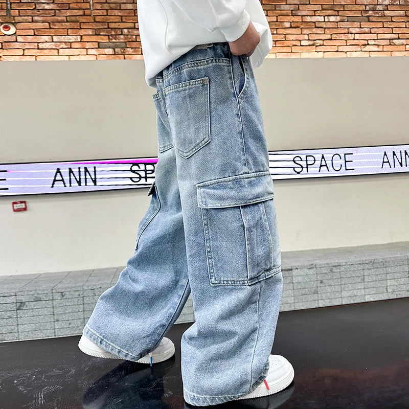 Person wearing light blue cargo jeans standing in front of a brick wall and sign.