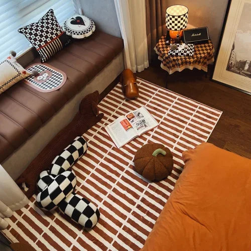 Cozy room with a brown bench, checkered pillows, and a striped rug.