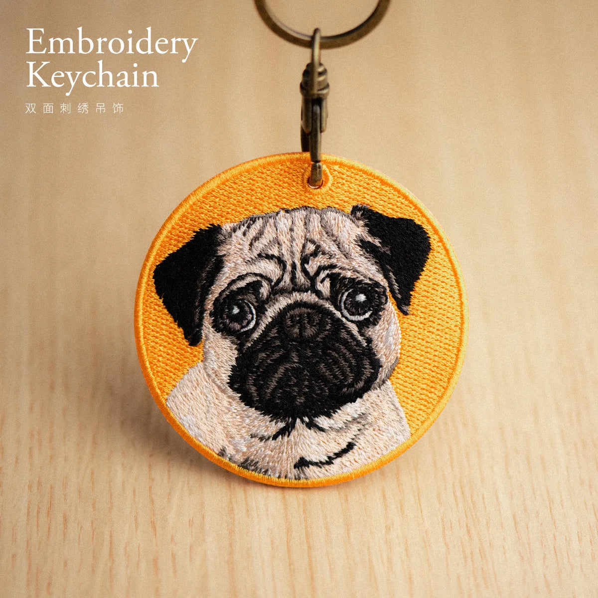 Embroidered keychain with a pug design on a wooden surface