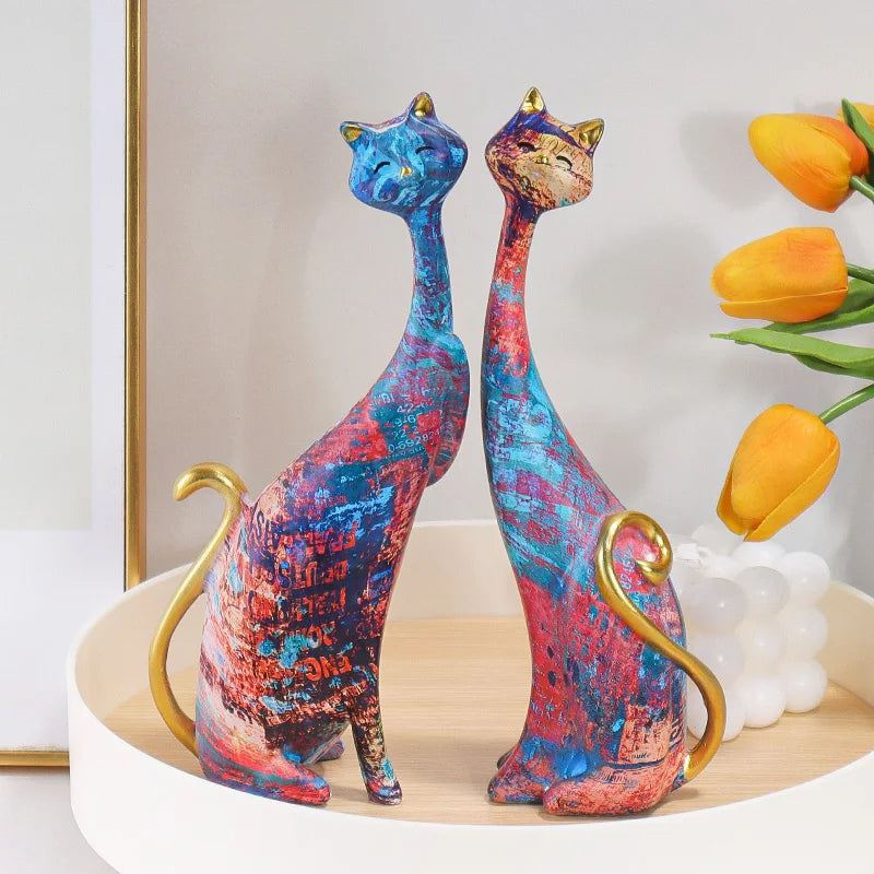 Pair of decorative resin cat sculptures with elongated modern silhouettes and artistic finishes, displayed as contemporary home decor on a tabletop.