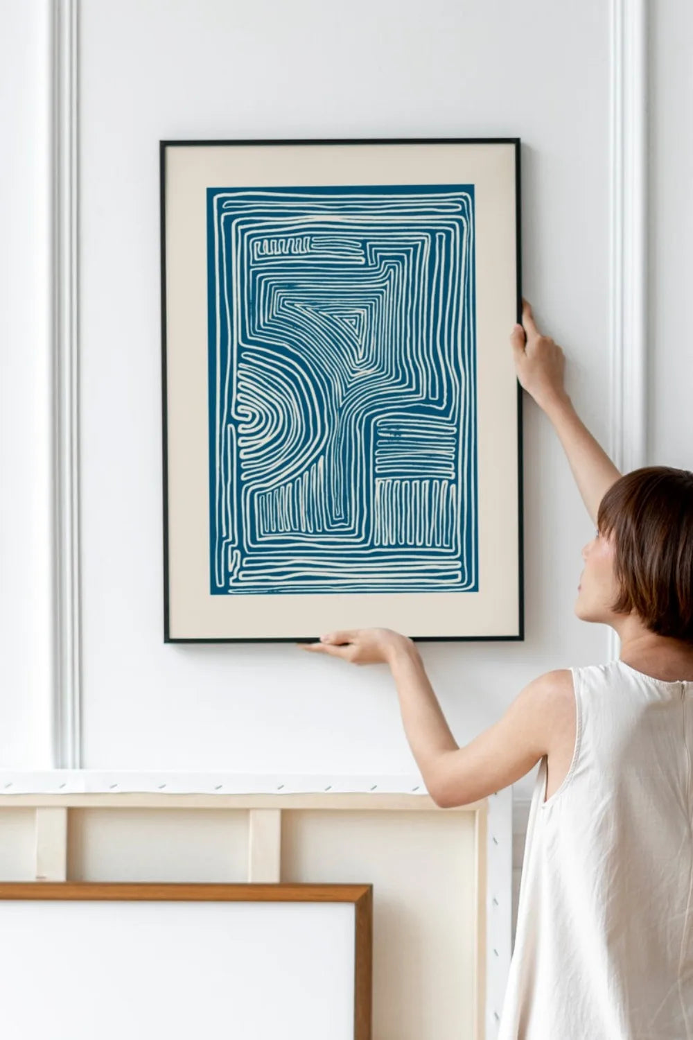 Person hanging an abstract art print on a wall