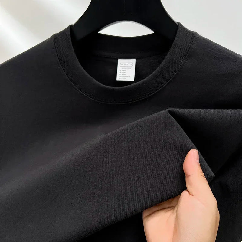Black t-shirt on a hanger with a hand touching the fabric