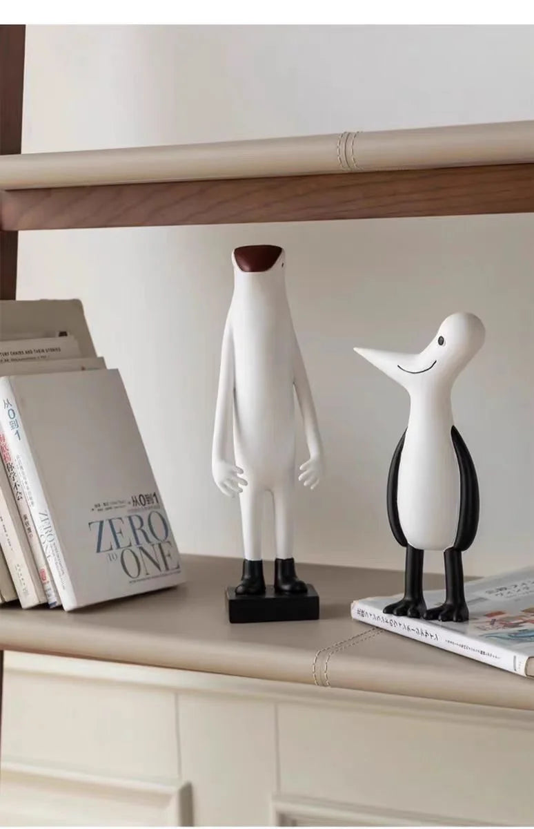 Two decorative statues on a shelf with books underneath