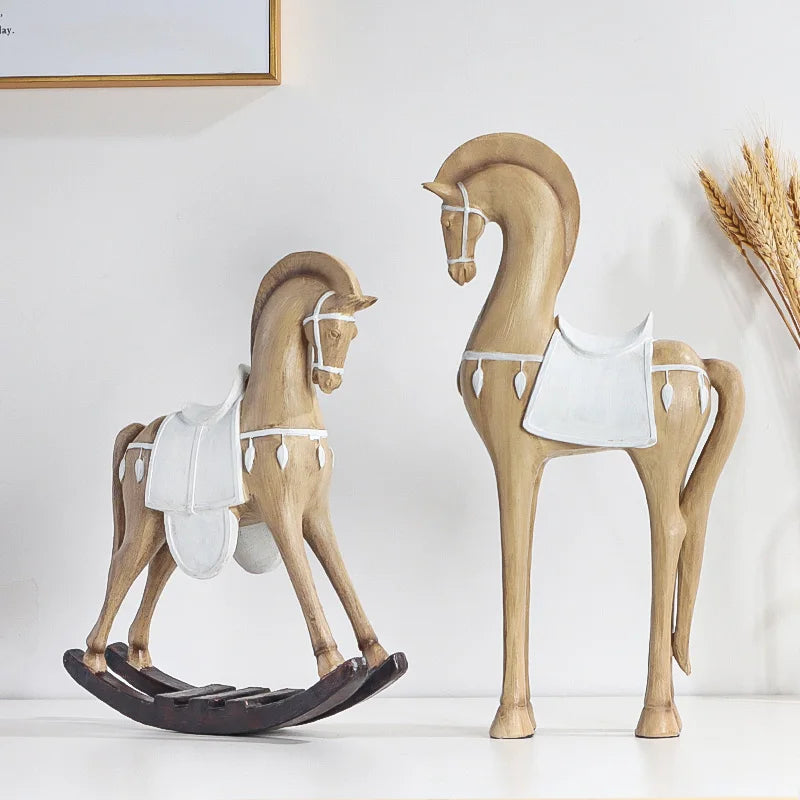 Two wooden horse sculptures, one with a rocking base, on a white surface.