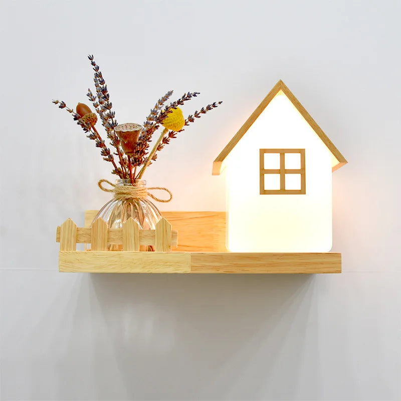 Wooden shelf with a house-shaped light and vase of flowers on a white background