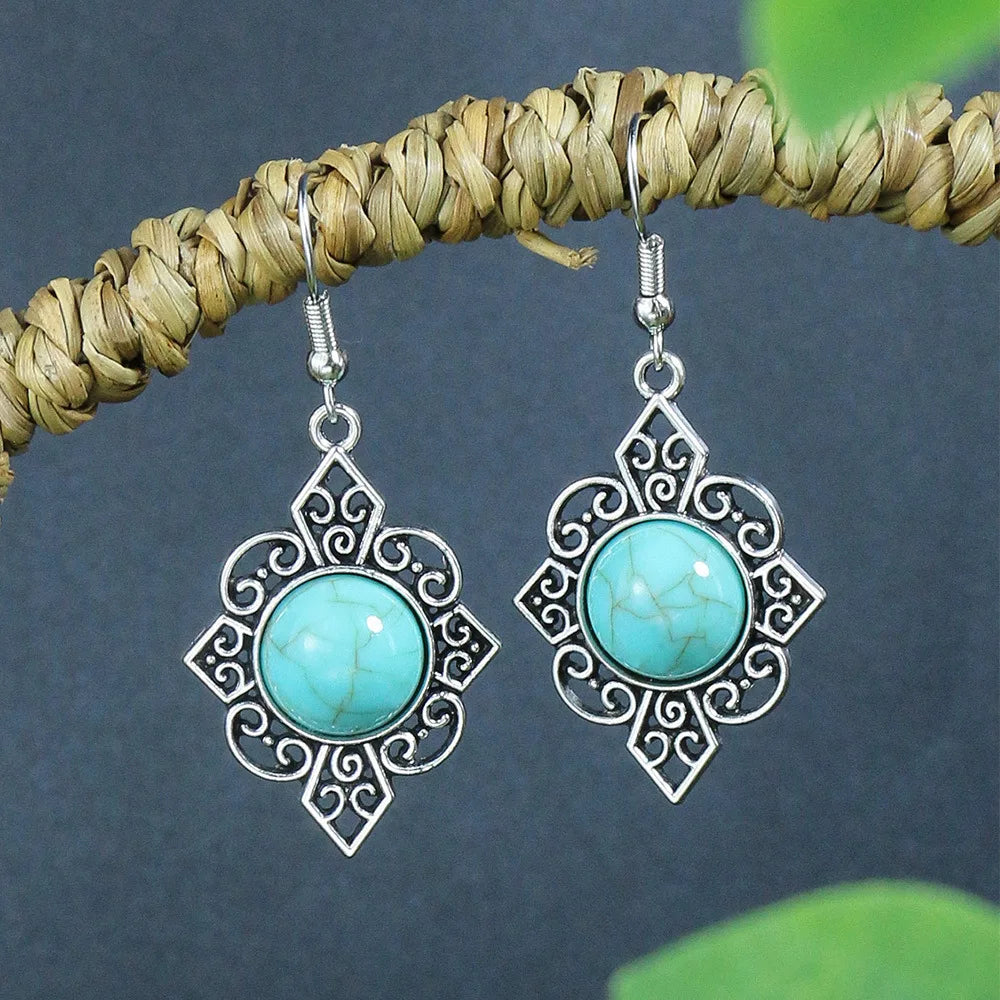 Pair of silver earrings with turquoise stones on a dark background