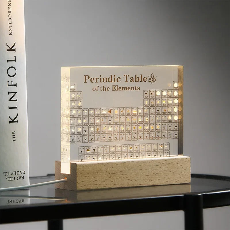 Luminous periodic table of elements on a wooden base with a book in the background