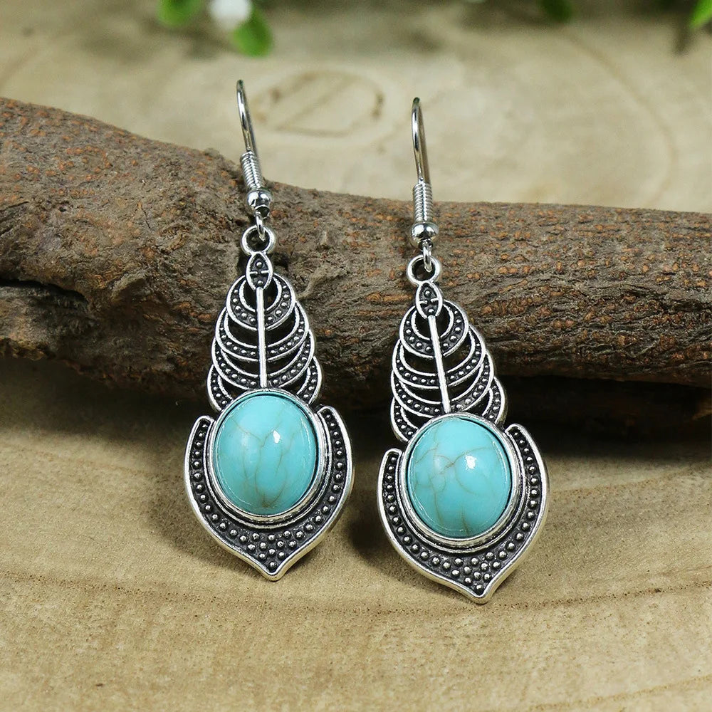 Pair of silver earrings with turquoise stones on a wooden surface
