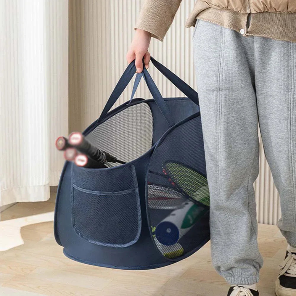 Person holding a blue pet carrier with items inside, standing in a room.