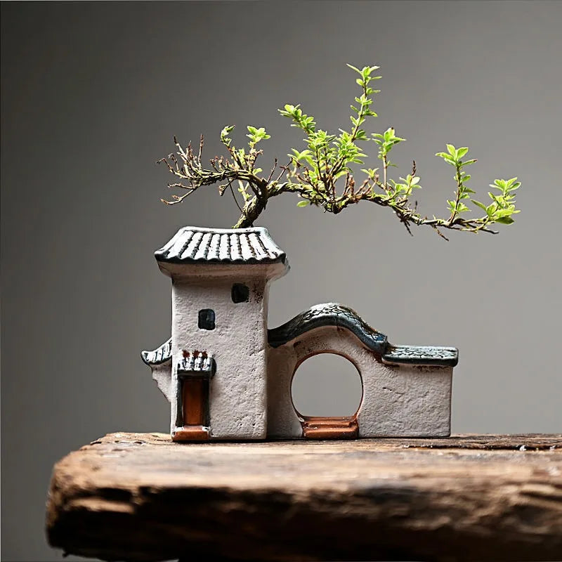 Ceramic house planter with Jiangnan style design featuring tiled roof and wooden door, used as a succulent or bonsai pot on wooden surface