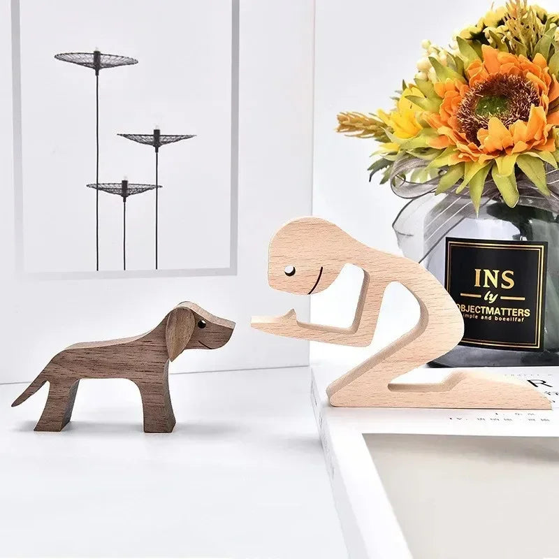 Wooden dog and monkey figurines on a white surface with a vase of flowers in the background.