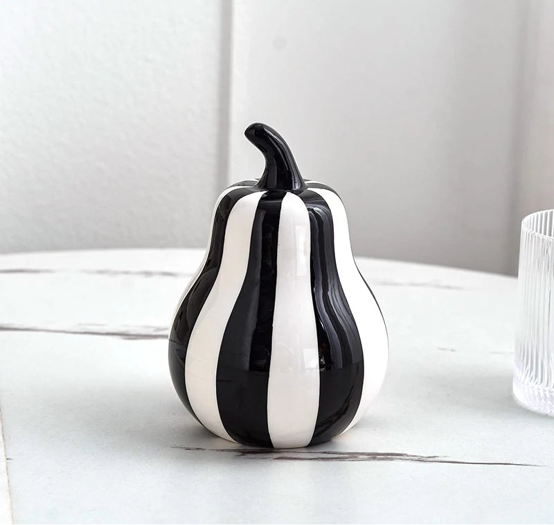 Black and white striped ceramic pear on a light surface with a neutral background