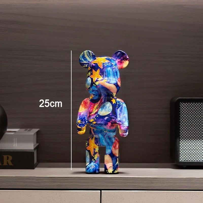 A colorful bear-shaped figurine standing on a shelf, with a vertical measurement line and the text '25cm' indicating height. The bear has a glossy multicolor space-like pattern in blue, purple, pink, yellow, and orange.