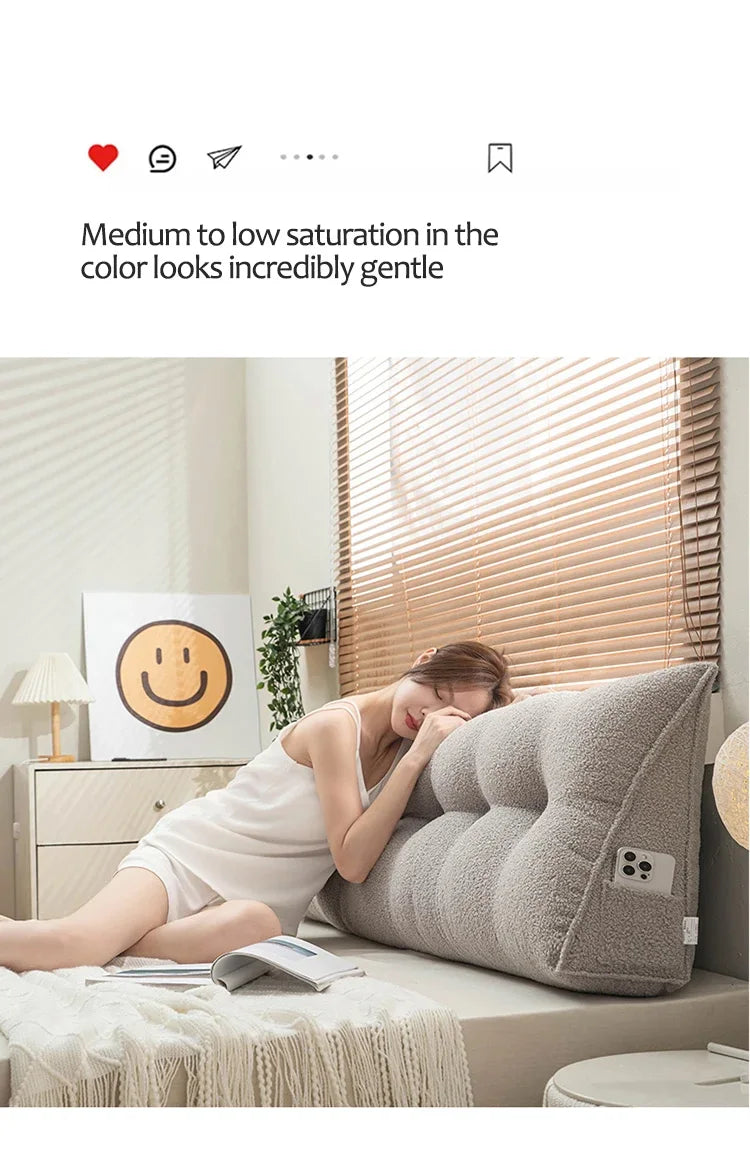 Woman lying on a bed with a wedge-shaped pillow, smiling emoji on wall